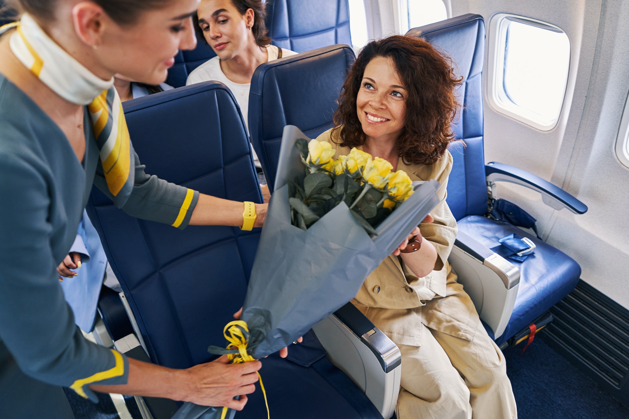 Flight attendant giving flowers to a female tourist