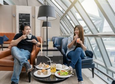 Asian couple sitting and eatting inn airport lounge when waiting the flight